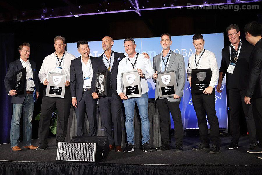 Jeffrey Gabriel of Saw.com standing on stage at NamesCon 2025, holding his Escrow.com Master of Domains Award alongside other industry award winners.